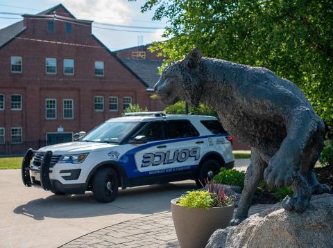 UNH Wildcat statue with a campus police car behind it